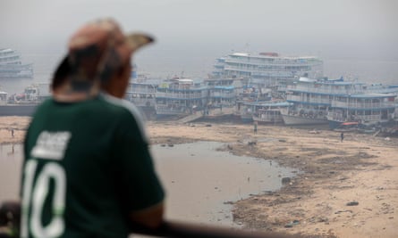 A man observes boats anchored in Rio Negro port as smoke haze from fires in the Amazon rainforest blankets the area in Manaus