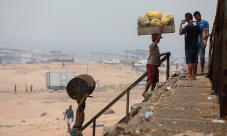 Men load products at Rio Negro port as smoke haze from fires in the Amazon rainforest blankets the area in Manaus